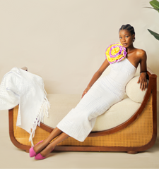 Woman in a white robe sitting on a modern chair with a neutral background