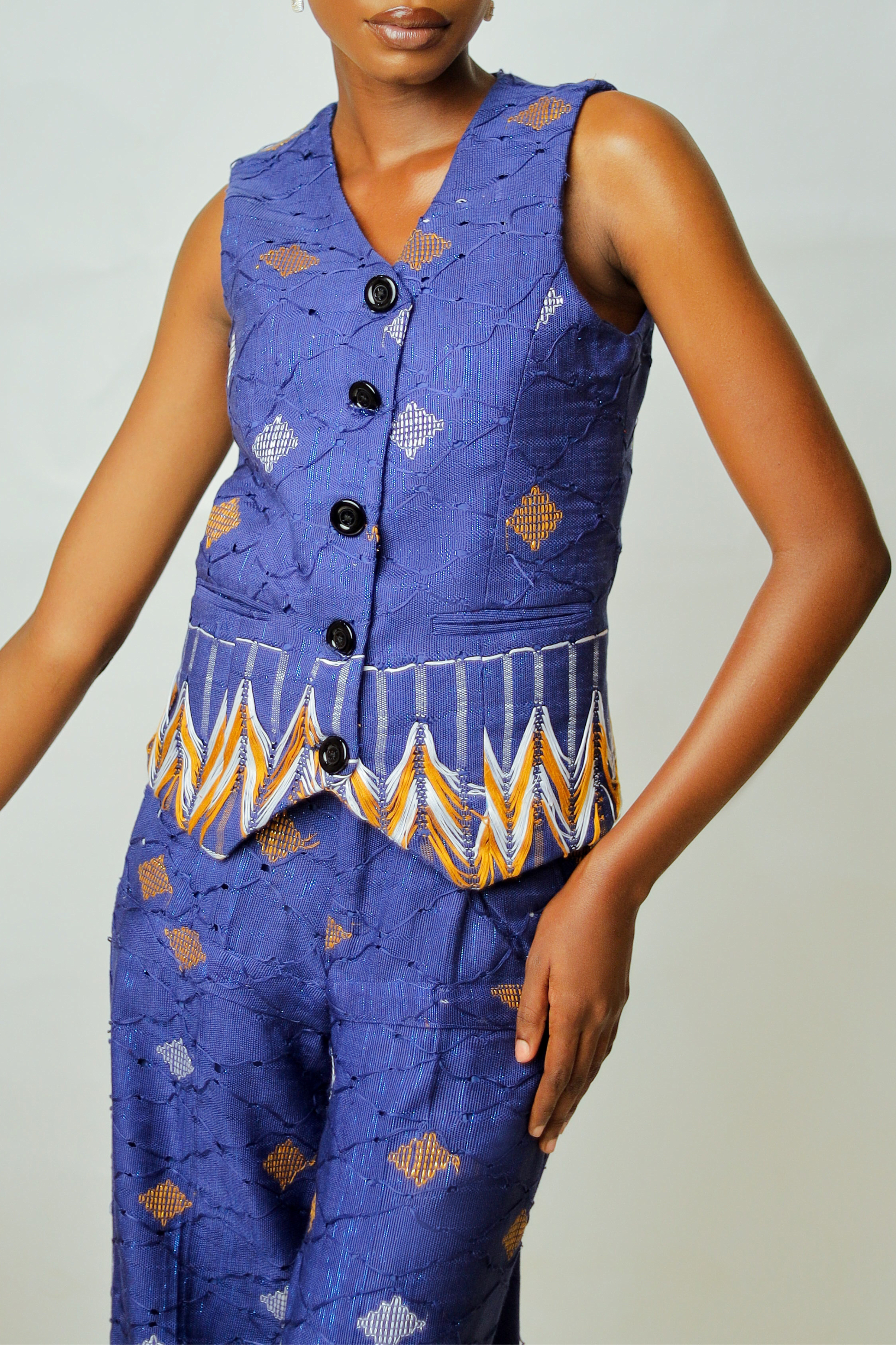 Woman wearing a blue patterned sleeveless top and pants against a plain background